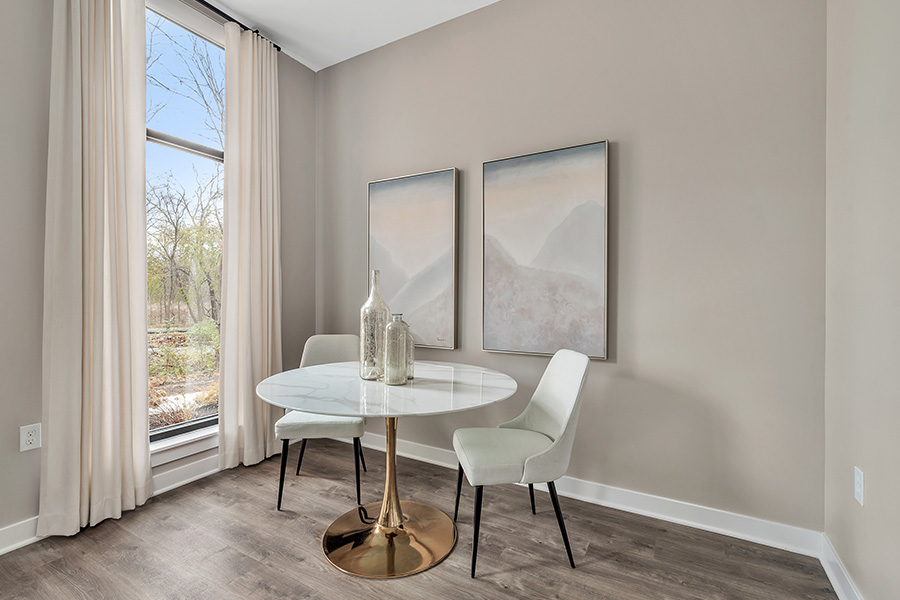 Sheer curtains on a long and tall window within a small breakfast nook located at Somo Flats Apartments.